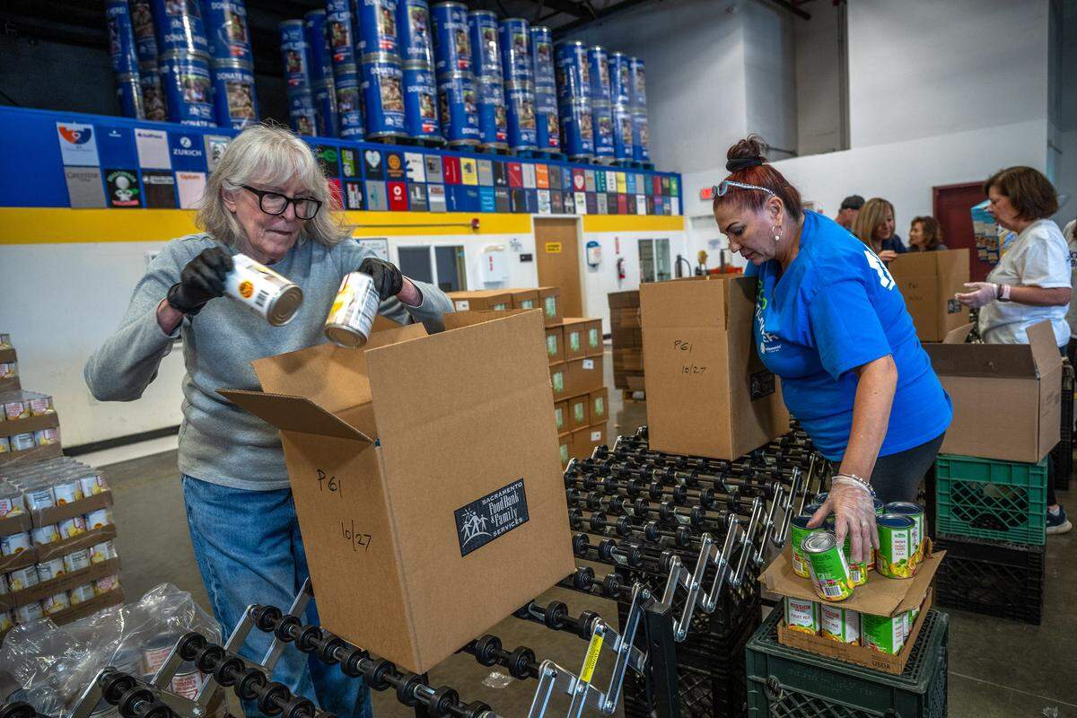 Volunteers Ann Vanderbyl, left, and Christina Johnson, right, pack canned food into boxes for seniors at the Sacramento Food Bank & Family Services in October.