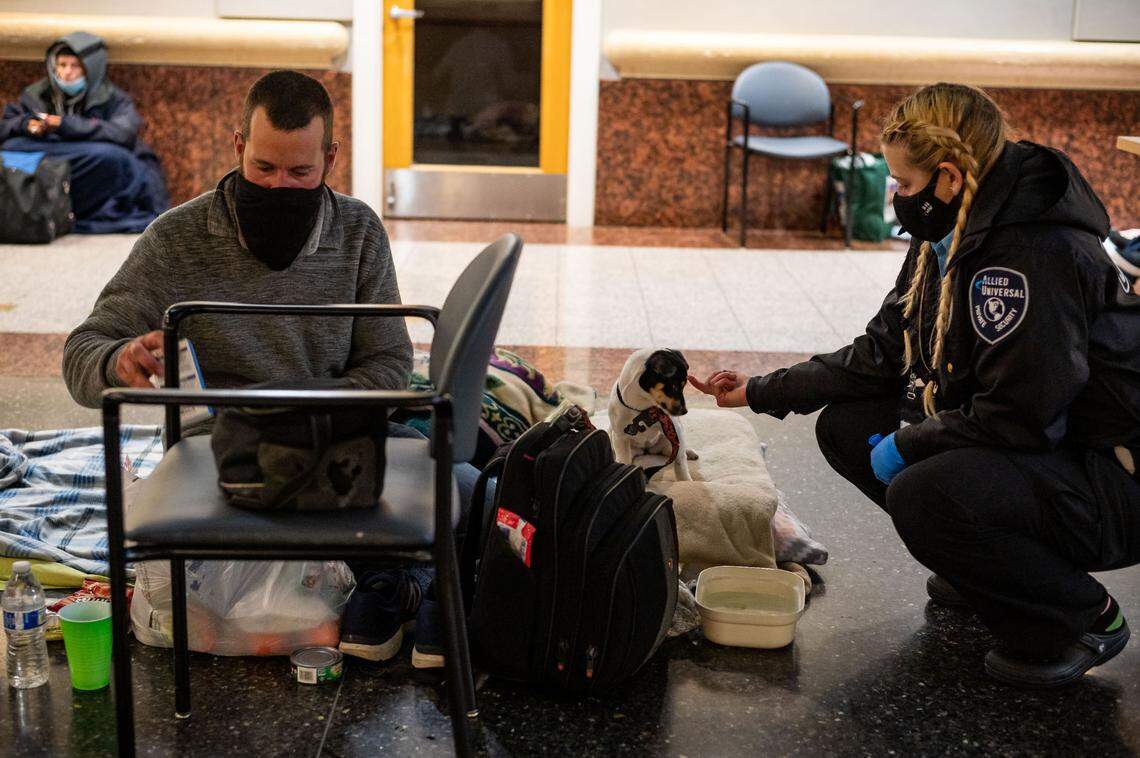 Homeless resident Anthony Munoz, left, settles in for the night as his 15-week-old puppy, “Baby Girl,” is made comfortable by visiting security personnel Klarissa Stipkovich at the warming center at Tsakopoulos Library Galleria on Wednesday, Jan. 27, in downtown Sacramento. Munoz said they stayed outside City Hall Tuesday night for the most severe winter storm of the season.