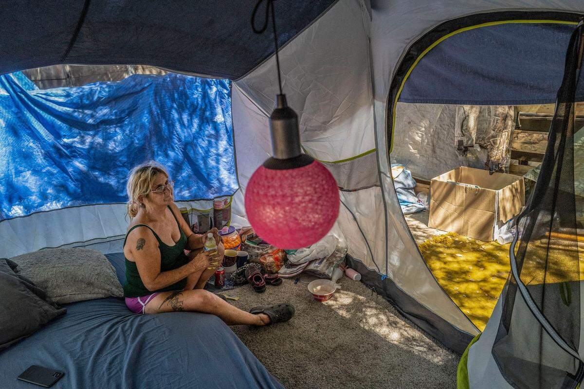 Gwen Mayse, 62, who decorated her tent with a pink lamp, tries to cool off with some lemonade in August, underneath a freeway overpass in north Sacramento. Just 10 days later, on Sept. 4, Mayse died, along with two of her dogs, when she fell asleep while driving in Tulare County.