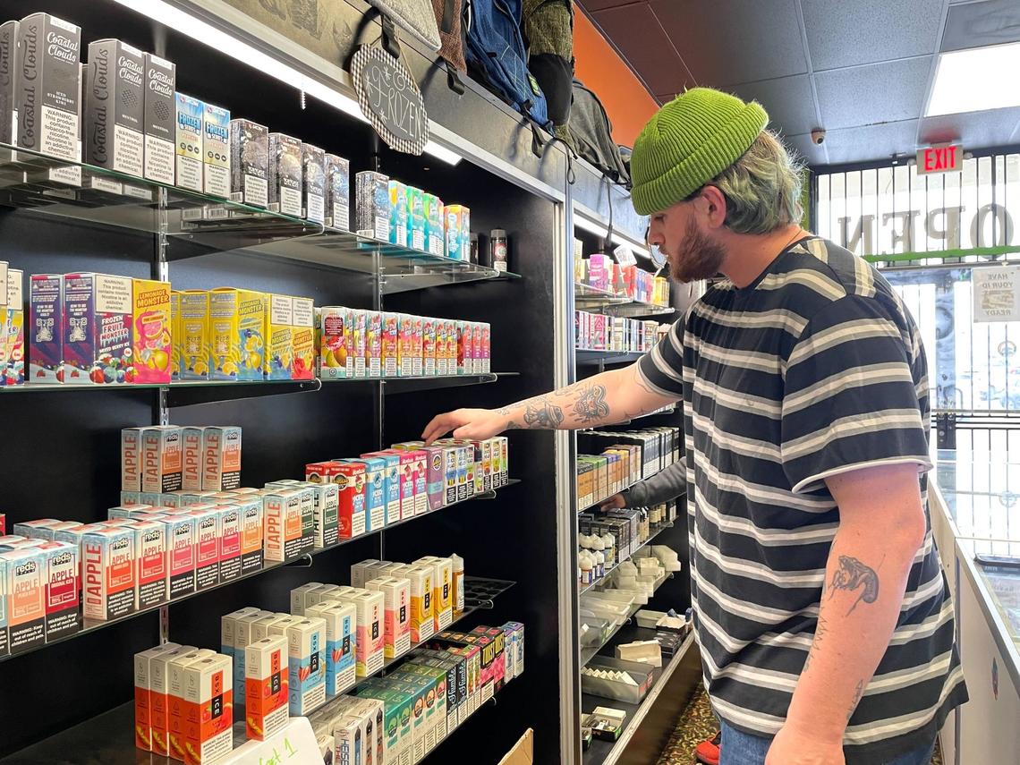 Dillon Carey, an employee of the Magma Vape & Smoke Shop, takes inventory of the store’s flavored tobacco products before taking them off the shelf on Wednesday in Citrus Heights.