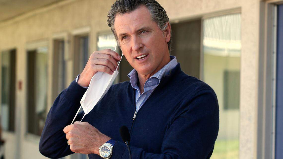 Gov. Gavin Newsom removes his face mask before giving an update on the state’s initiative to provide housing for homeless Californians to help stem the coronavirus, during a visit to a Motel 6 participating in the program in Pittsburg, Calif., Tuesday, June 30, 2020. State Health and Human Services Secretary Dr. Mark Ghaly said California will lift its mask mandate on June 15.