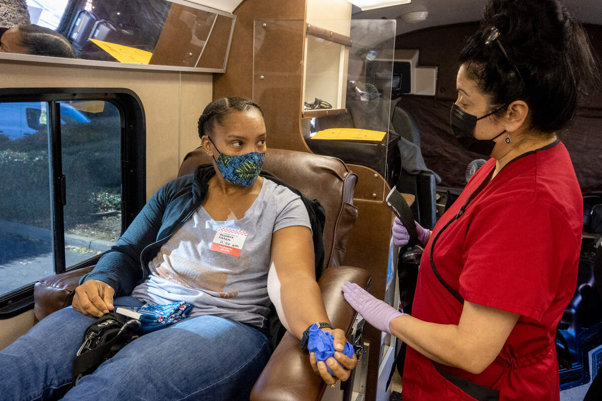 Shavana Fisher, talks with phlebotomist Laura Pinola before donating blood at the Red Cross moble bus outside of the UC Davis Home Care Services building in Sacramento on Wednesday, Nov. 24, 2021. The Red Cross is asking for $7,700 to fund the in-depth testing, typing and matching of blood for people living with sickle cell disease.