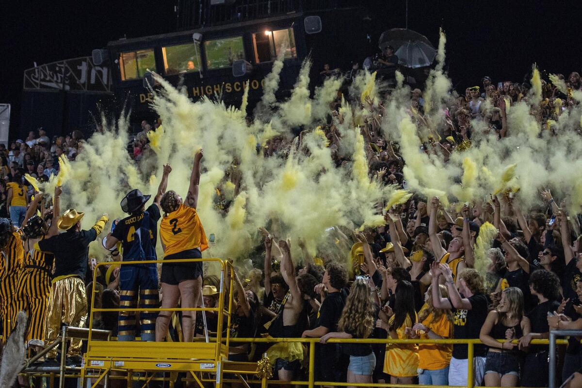 The Del Oro student section throws powder in the air before the end of the second quarter during the game against the Menlo-Atherton Bears on Friday at Del Oro High School in Loomis.