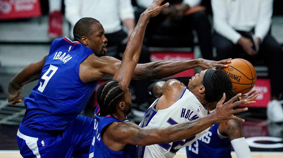 Los Angeles Clippers center Serge Ibaka (9) blocks a shot by Sacramento Kings center Richaun Holmes, right, during the third quarter of an NBA basketball game Wednesday, Jan. 20, 2021, in Los Angeles. Los Angeles Clippers forward Kawhi Leonard, center, also defends. (AP Photo/Ashley Landis)