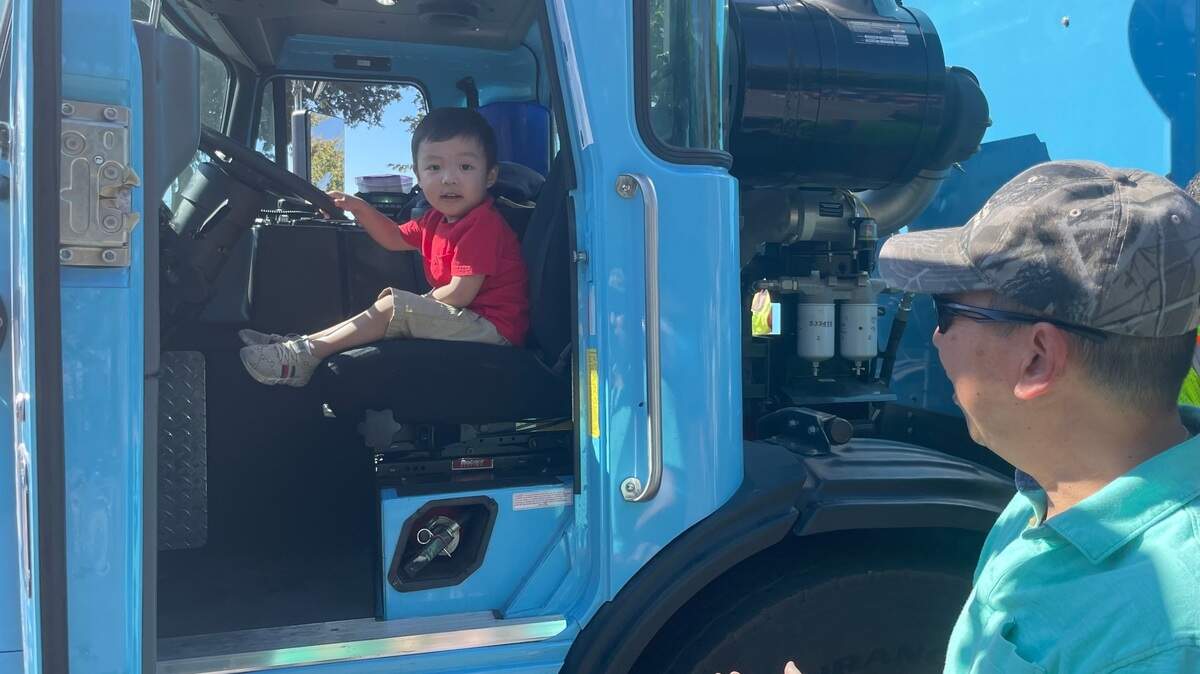 Oai Lam talks with his 2-year-old son, Alvin, who took over the driver’s seat of a Sacramento garbage truck at Saturday’s Highwater Jamboree.