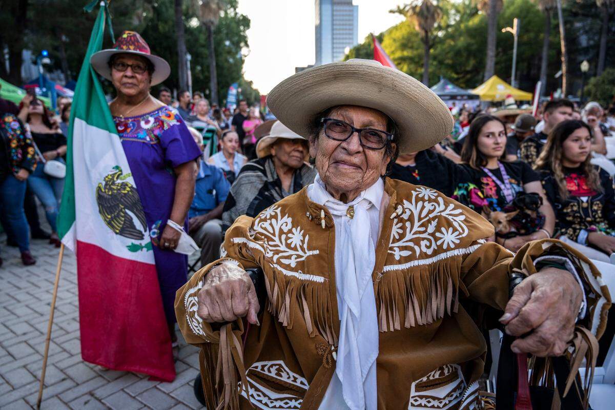 Sacramento resident Angelbertha Cobb, 90, mother of 19 and a Mexican movie actress who founded the city’s first ballet folklorica, watches the Mexican Day of Independence festivities as Maria Lopez, 70, left, holds the Mexican flag.