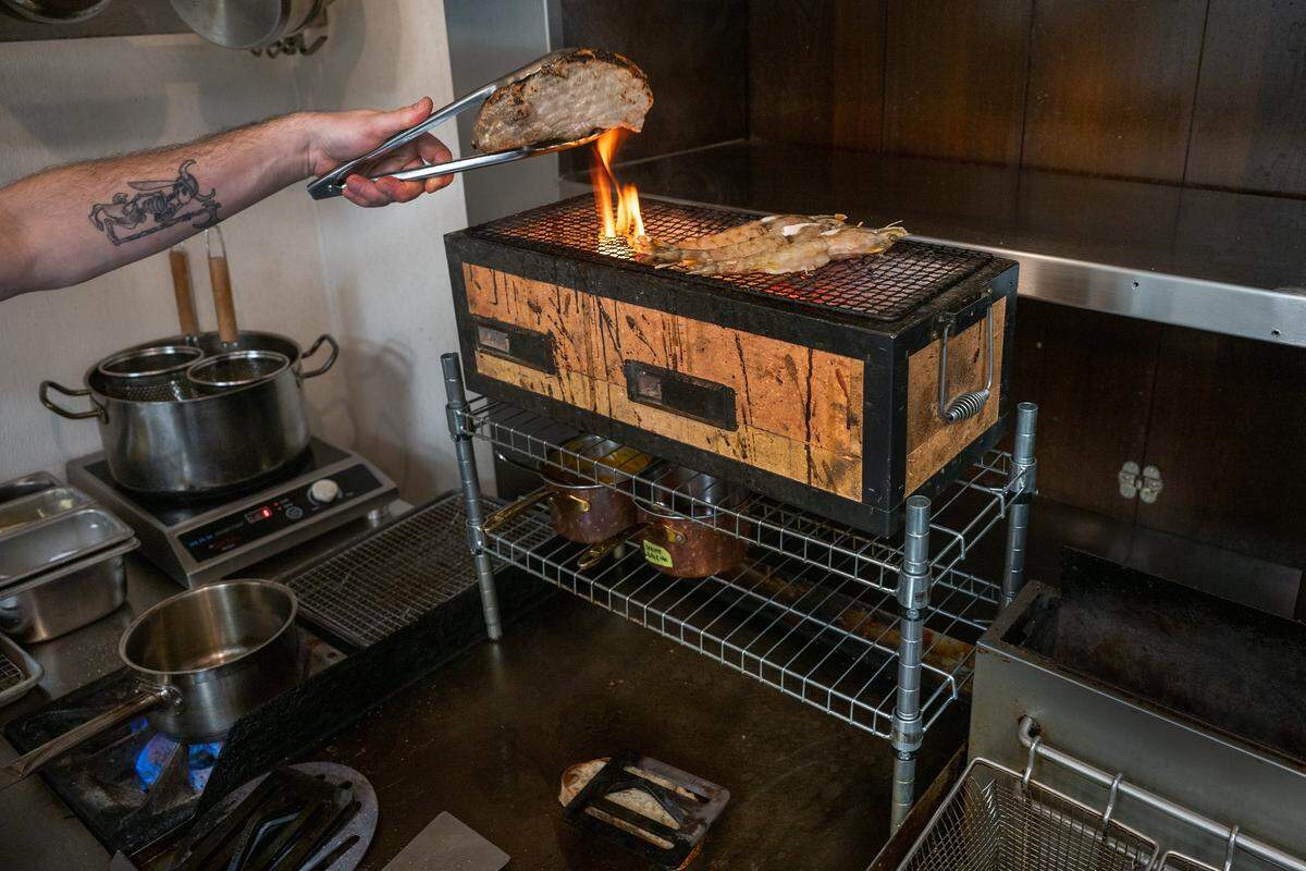 Executive Chef Galice Ryan uses a Japanese grill to cook a double-cut pork chop and prawns in the Star Lounge’s small kitchen last week in Sacramento.