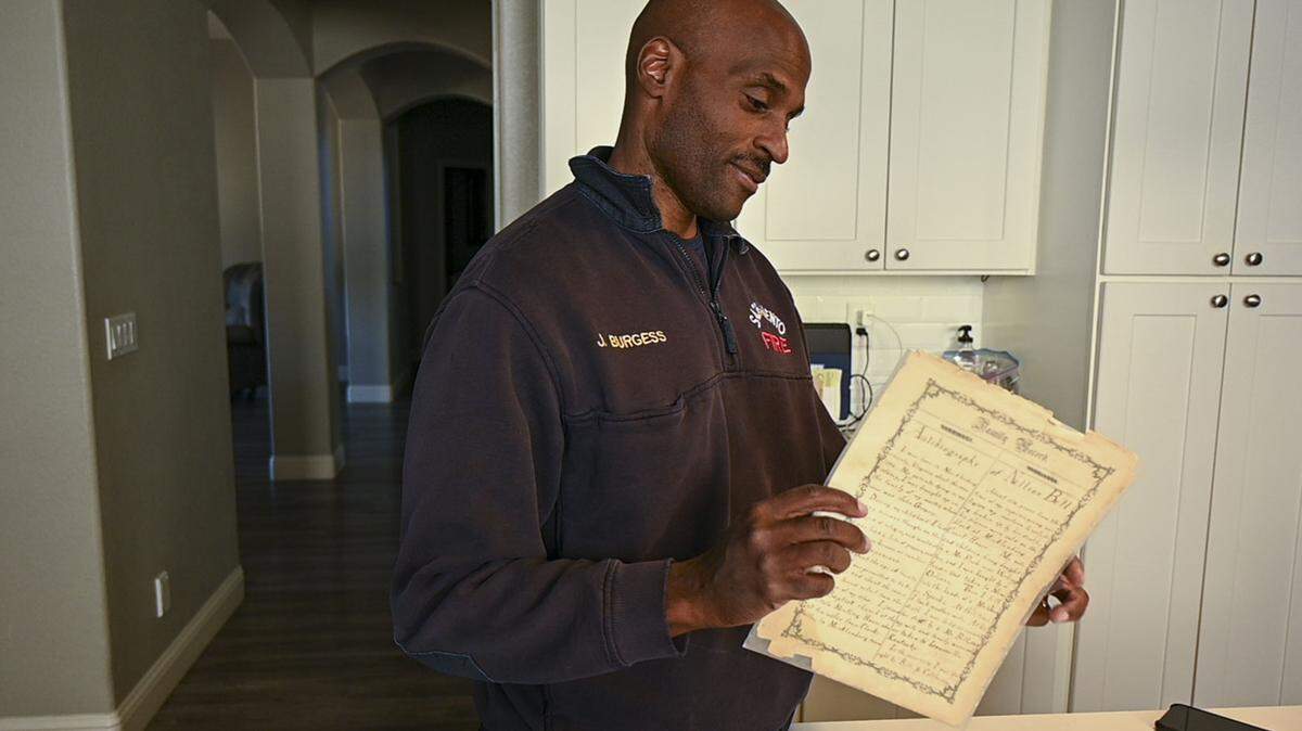 Jonathan Burgess looks at an autobiography written by his great-grandfather Rufus Burgess on Wednesday, March 16, 2022, at his home in south Sacramento. Burgess documented his family’s history as early Black settlers in Coloma and used it to press for reparations and land restoration before his death May 11 at age 52.