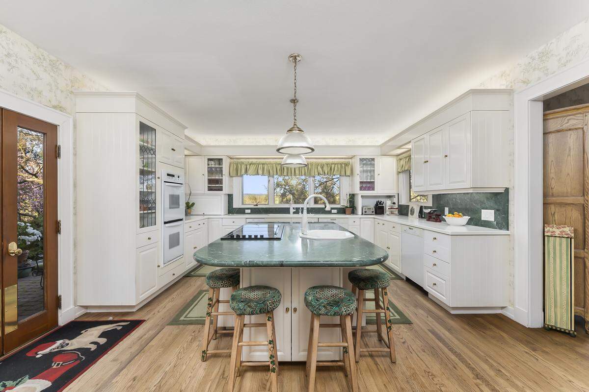 A large modern kitchen with leaded‑glass cabinets opens to a cozy sitting area and butler’s pantry, blending 1902 character with contemporary comfort.
