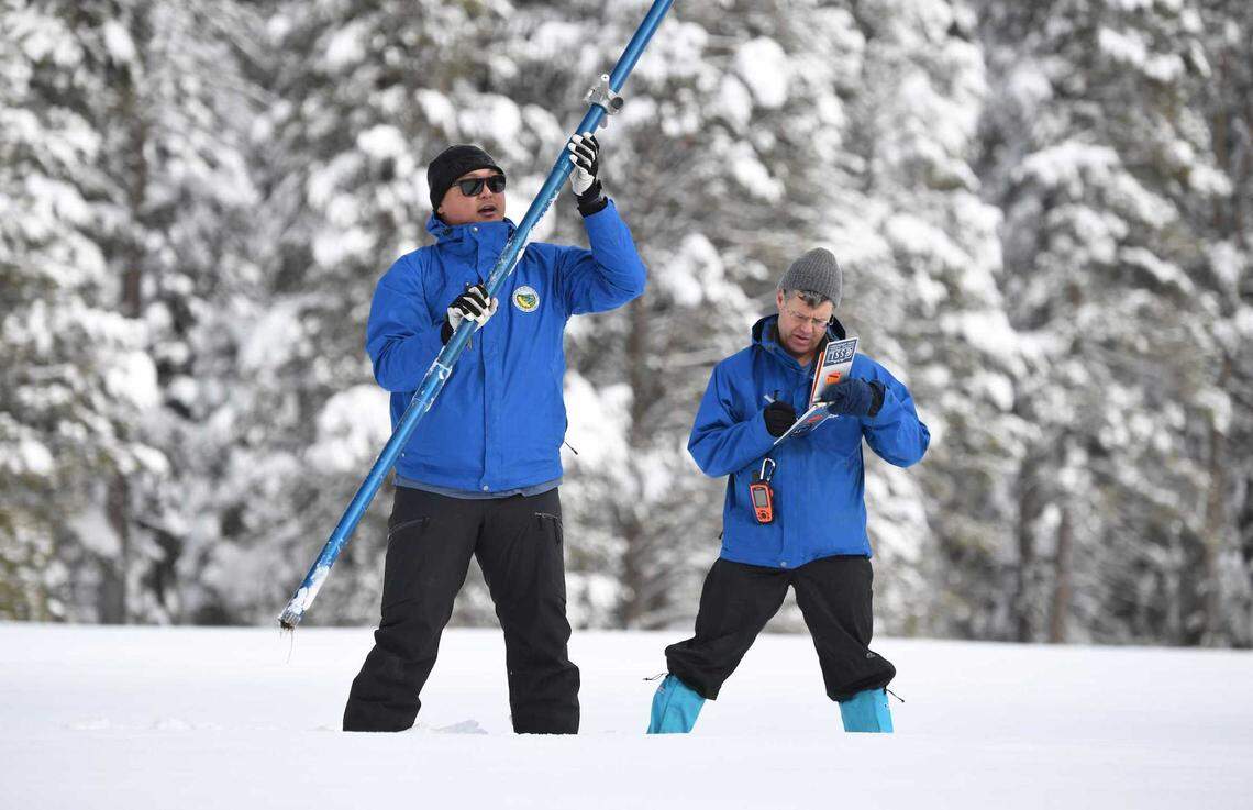 Sean de Guzman, left, chief of the Department of Water Resources’ snow surveys, and Andy Reising,  a water resources engineer for the state, review the first snowpack measurement of the season Tuesday at Phillips Station in El Dorado County. The state’s snowpack measured 174% of the average depth for Jan. 3 and was more than 60% of the April 1 average.