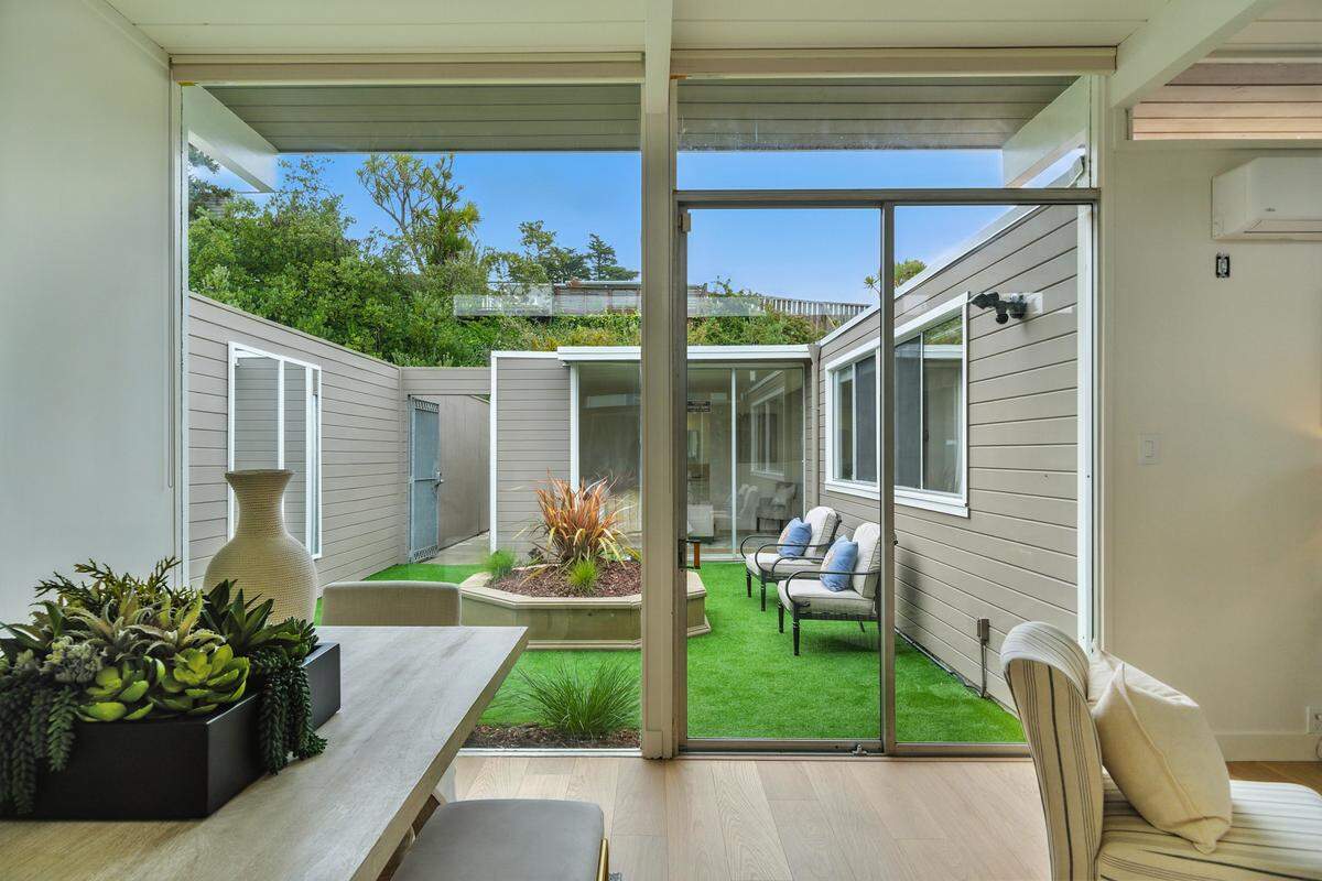“An expansive living and dining room with soaring ceilings and oversized windows opens to one of three private gardens. A separate family room just off the kitchen enjoys its own green outlook.”
