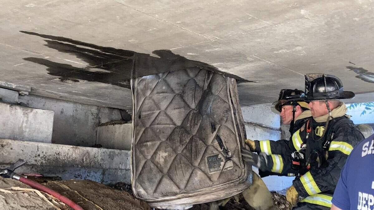 Sacramento firefighters remove a mattress from an overpass on Highway 160 on Sunday.