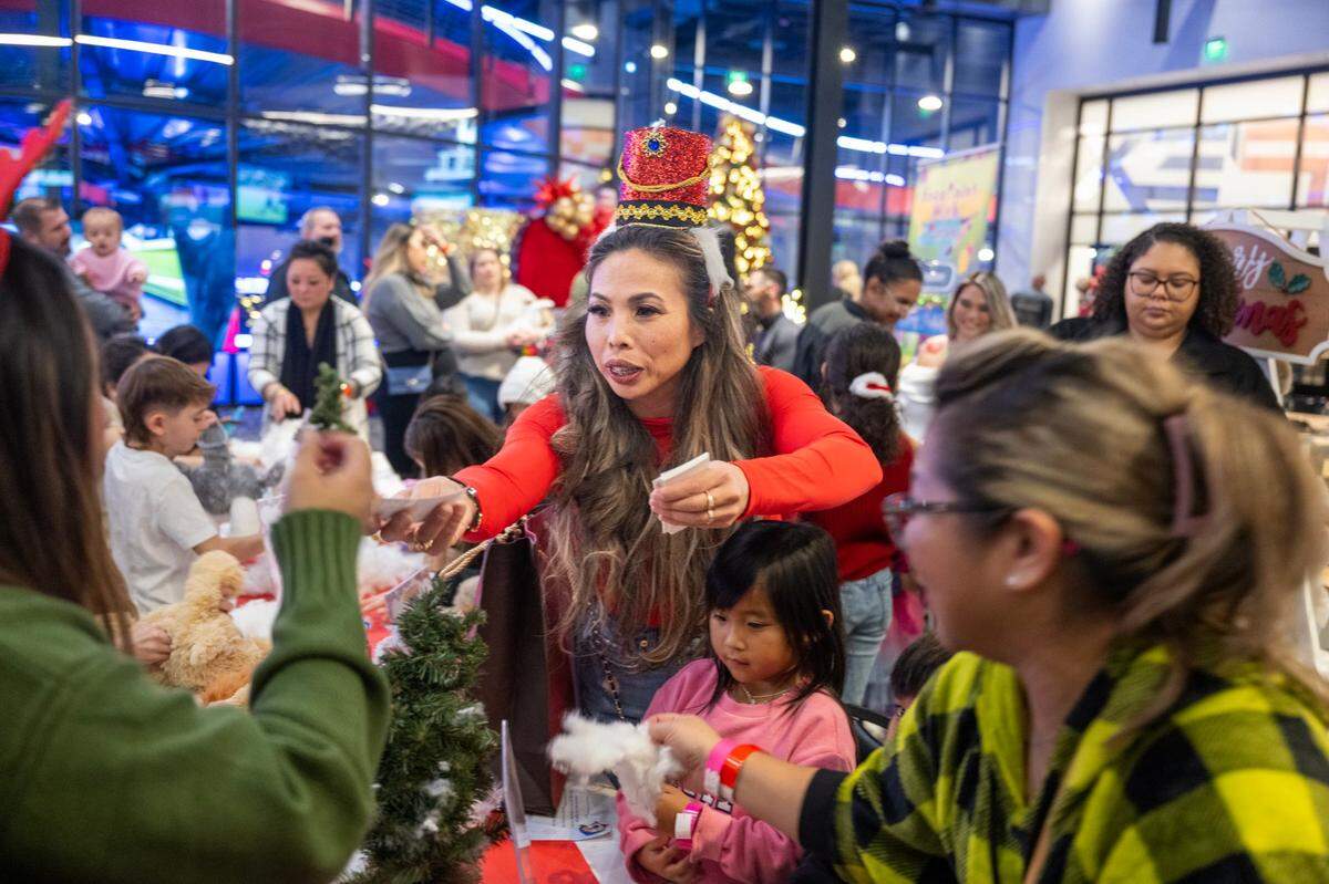 Distributing arcade and drink tickets, attorney Anh Phoong reaches over a table where children create stuffed animals at her annual Phoong Law Christmas party earlier this month at The Apex at Red Hawk casino.