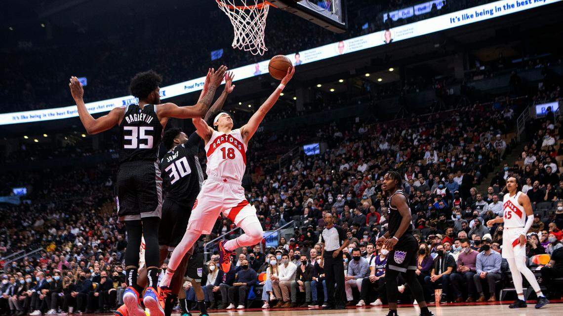 Toronto Raptors’ Yuta Watanabe (18) scores on Sacramento Kings’ Damian Jones (30) and teammate Marvin Bagley III during the first half of an NBA basketball game in Toronto, Monday, Dec. 13, 2021. (Chris Young/The Canadian Press via AP)