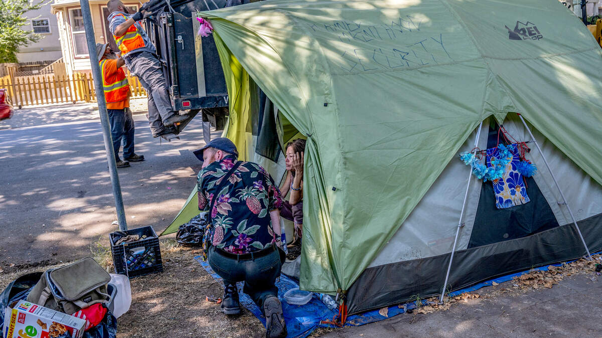 Jared Johnson,  activista por las personas sin hogar, habla con una mujer en una tienda de campaña mientras unos trabajadores realizan una redada de personas sin hogar en la C Street de Sacramento en 2023.