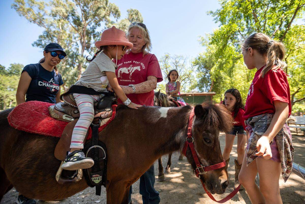 Gianna Macias, 2, is helped onto a pony by Land Park Pony Rides owner Marilyn Hagemann on the last day of operations for the longtime attraction Monday at William Land Park in Sacramento. Giannas mother, Johanna Macias, of Sacramento, watches at left, and Hagemanns granddaughters, Sierra and Shasta Caldes, assist at right.