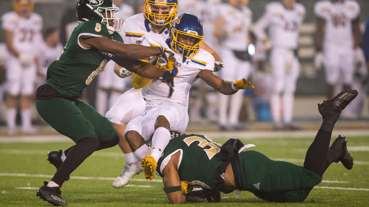 South Dakota State Jackrabbits wide receiver Tyler Feldkamp (8), center, holds on to the ball as he’s taken down by Sacramento State Hornets safety Marcus Aponte (8), left, and linebacker Armon Bailey (30) after bobbling a kickoff return during a playoff game in 2021 at Hornet Stadium in Sacramento.