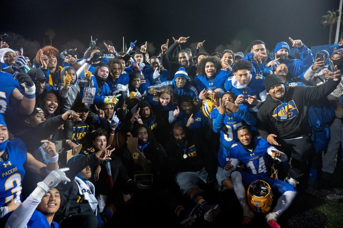 The Grant Pacers football teams poses for a photo with the state trophy after the 2022 CIF State Football Division III-AA Championship on Saturday, Dec. 10, 2022, at Grant High School in Sacramento. The Pacers won 36-34.