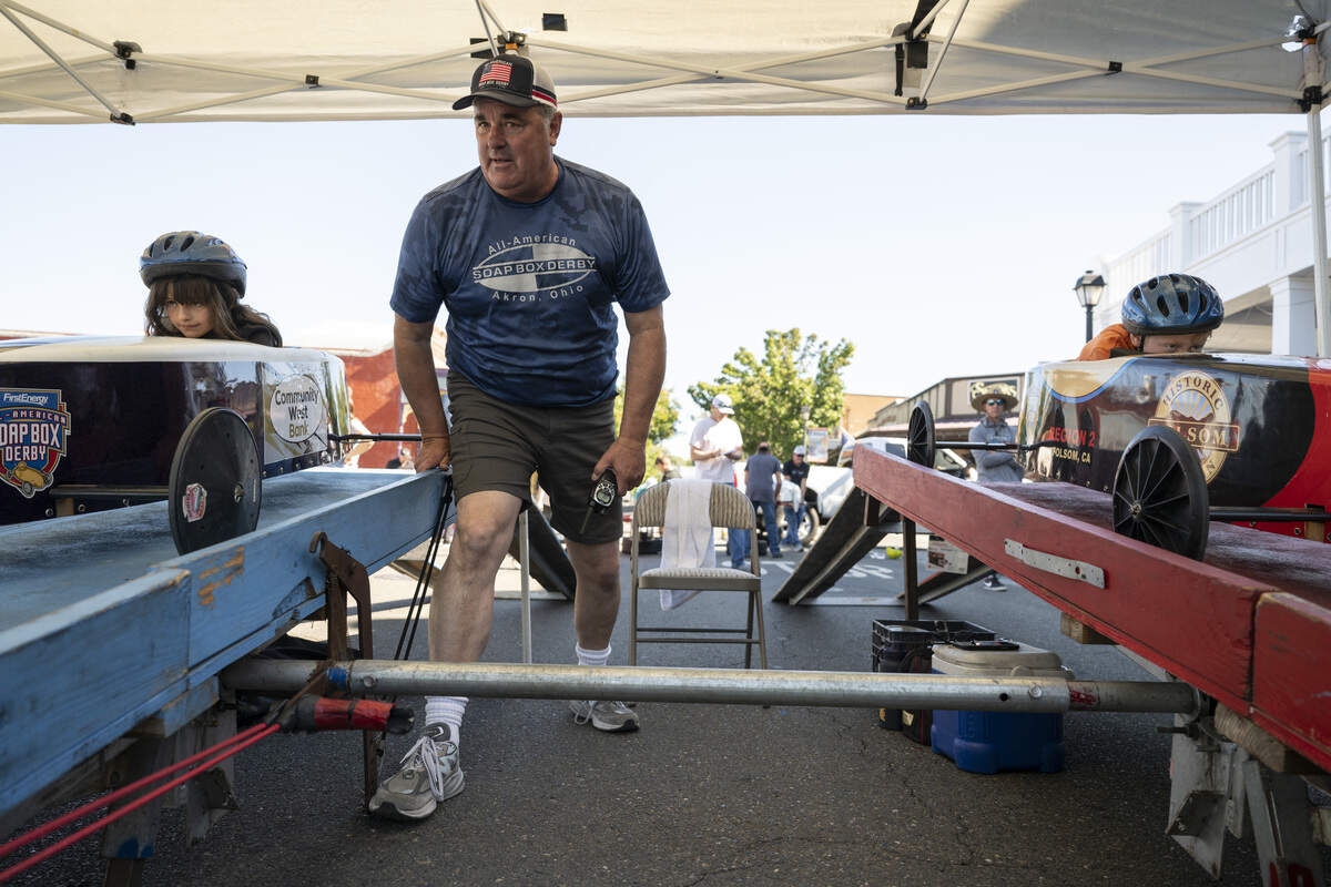 David Stagnaro, center, the race director for Northern California Soap Box Derby, releases a lever to send racers down the incline during the Folsom Historic District’s All-American Soap Box Derby in Folsom on Sunday, Oct. 5, 2025.