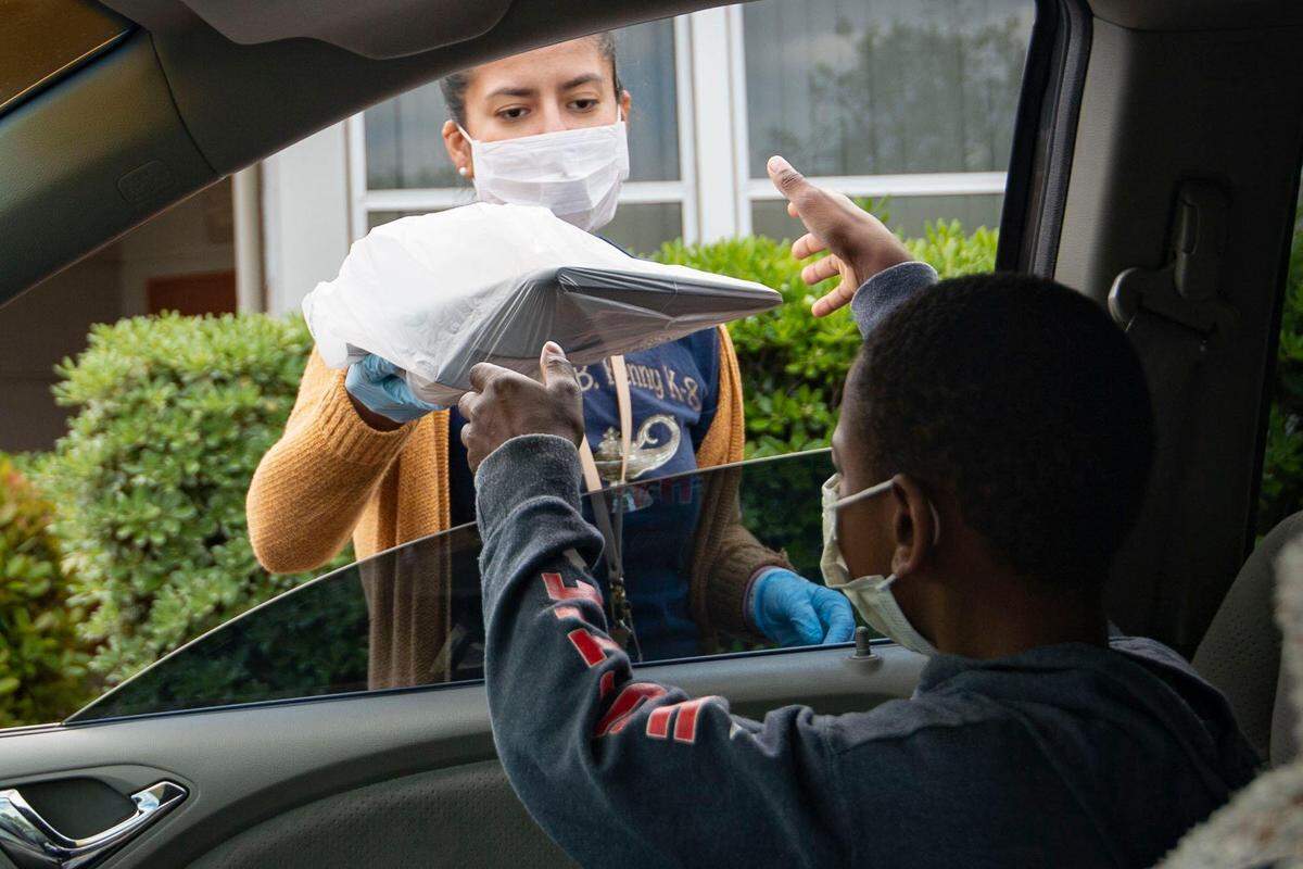 A third grade student at Father Keith B. Kenny Elementary School in Oak Park takes a laptop from Sacramento City Unified School teacher Sara Nava to use while distance learning during the coronavirus pandemic in April 2020.