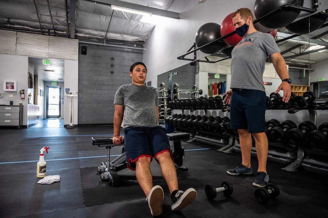 Student Daniel Okino, left, 21, exercises as trainer Bobby Best demonstrates proper form at Fitness Rangers in East Sacramento on Monday, July 13, 2020. California Gov. Gavin Newsom announced Monday that gyms and fitness centers would close again as coronavirus cases spike across the state.