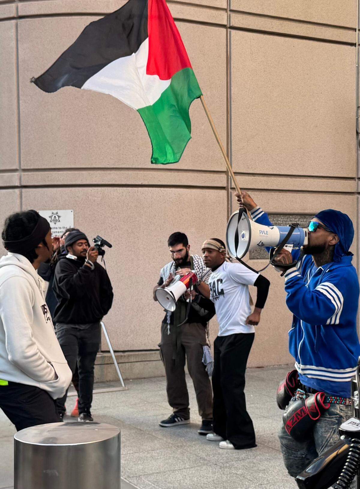 As a supporter waves a Palestinian flag Tuesday, Stevante Clark, second from right, tells protesters that his brother’s name is synonymous with those of many people who have been unjustly killed worldwide.