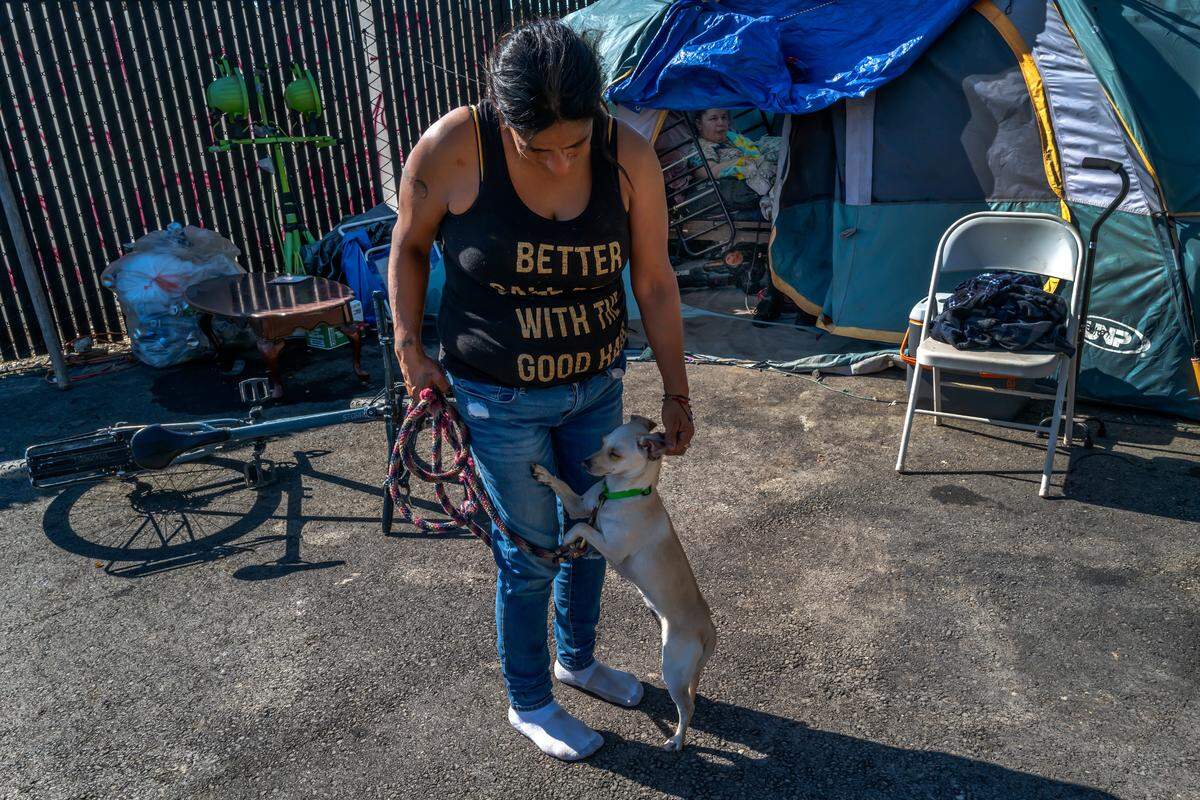 Julie Maestas plays with her dog Snowy at Camp Resolution in 2022. Maestas received a Lifeline phone through the Supplemental Nutrition Assistance Program, but the program only provided one year of service. 