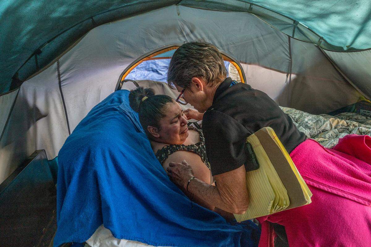 Tracey Knickerbocker, case manager for Hope Cooperative, leans in to hug Holly Porter, who is “functionally quadriplegic” and living in a tent. Porter had just confided to Knickerbocker that doctors told her two years ago she only had five years to live. She said she appreciated Knickerbocker consistently visiting and trying to help her.