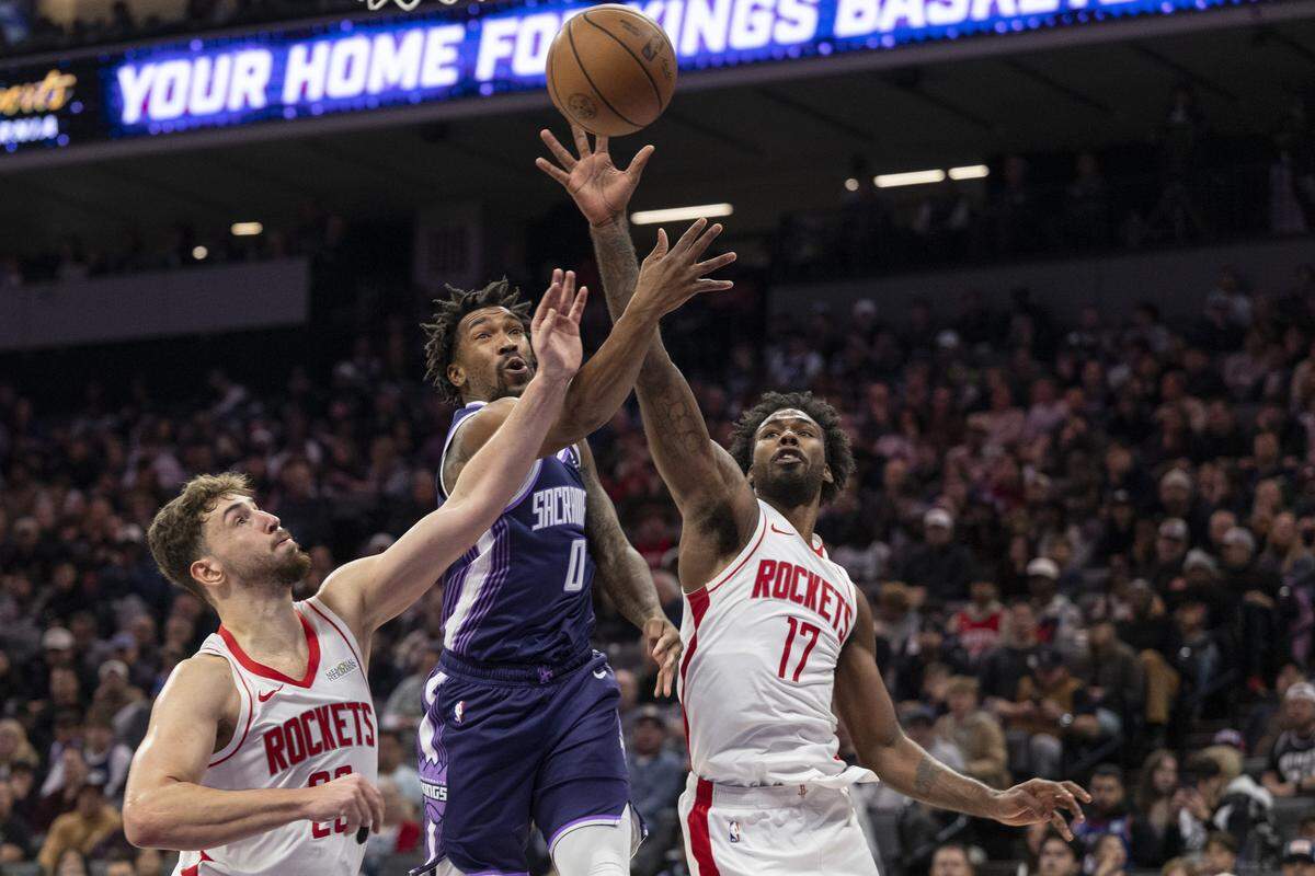 Sacramento Kings guard Malik Monk (0) fights for the ball with the Houston Rockets’ Alperen Sengun (28) and Tari Eason (17) at Golden 1 Center in Sacramento on Sunday.