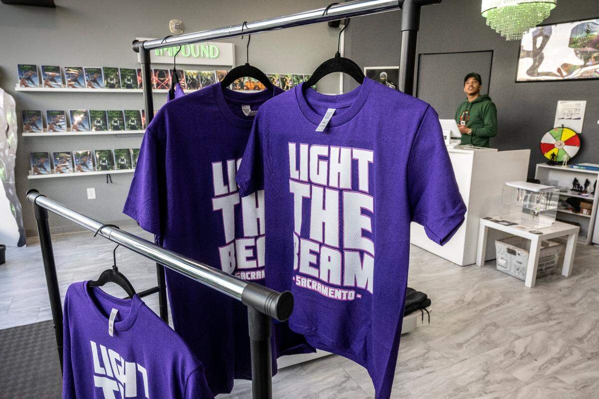 Shirts emblazoned with the “Light the beam” slogan are on display at Impound Comics at Downtown Commons on Wednesday. Owner Brent Trayce Sands, right, started selling them after the team’s Nov. 15 victory against Brooklyn.