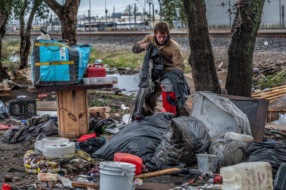 Joe Hill tries to salvage his and his wife’s clothing and move them onto a trailer that he hopes a friend can tow before city crews bulldoze his belongings during a homeless sweep on Auburn Boulevard on Wednesday. In the foreground, a plastic jug reads “out of gas.” He said his wife just got out of the hospital after suffering burns from a fire at their last camp. ”I got stress of making sure she stays healthy and not getting infected, this and them,” he said, ponting to the bulldozer down the street.
