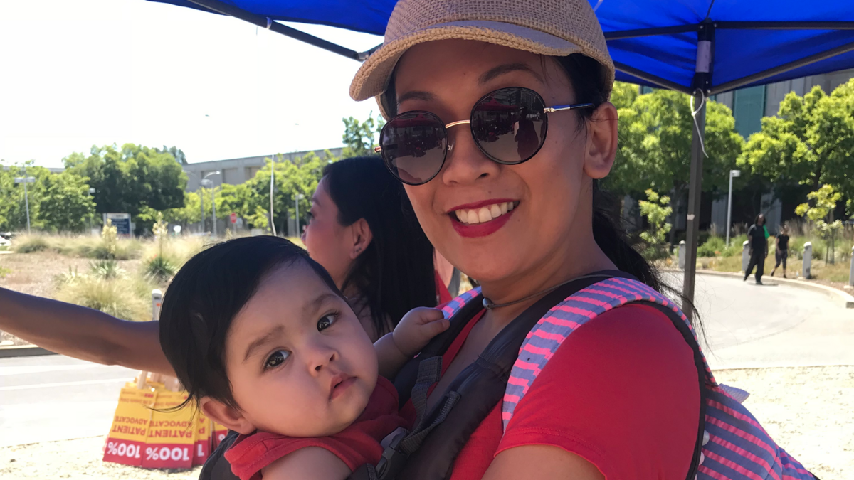 Abigael Dela-Garcia, a nurse in the medical surge unit at the UC Medical Center, joins the picket line, carrying her 9-month-old daughter, Anastasia, on Wednesday, May 9, 2018.