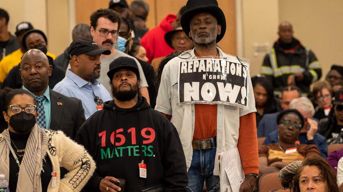 Morris Griffin, wearing a sign that says “reparations now,” waits in a line to speak during public comment on Saturday, March 4, 2023, at a meeting of the California Reparations Task Force, which convened for a second day at the California Environmental Protection Agency in Sacramento to study reparations proposals for Black Californians.
