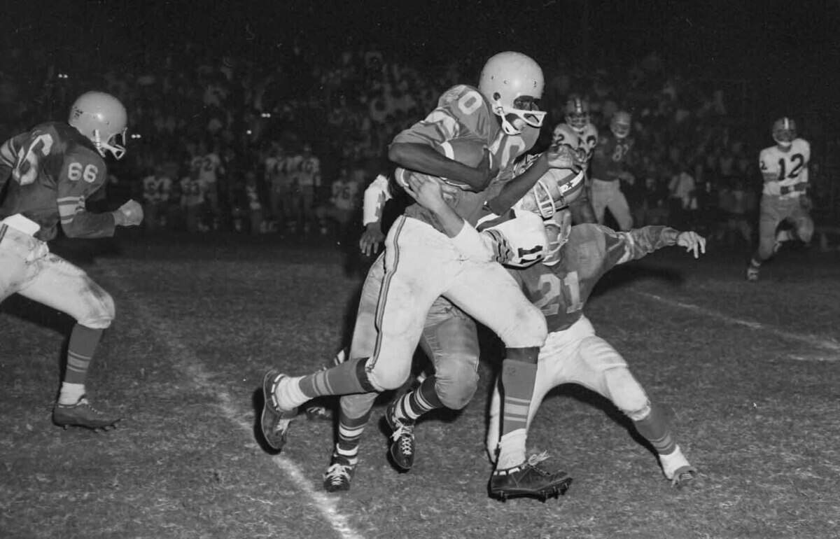 Del Campo Cougars halfback Dusty Baker drags Encina's Rick Ellsworth during a 20-yard carry on Sept. 30, 1966, as Dennis Kludt (21) looks for a block. Baker rushed for 116 yards on 21 carries and two touchdowns.