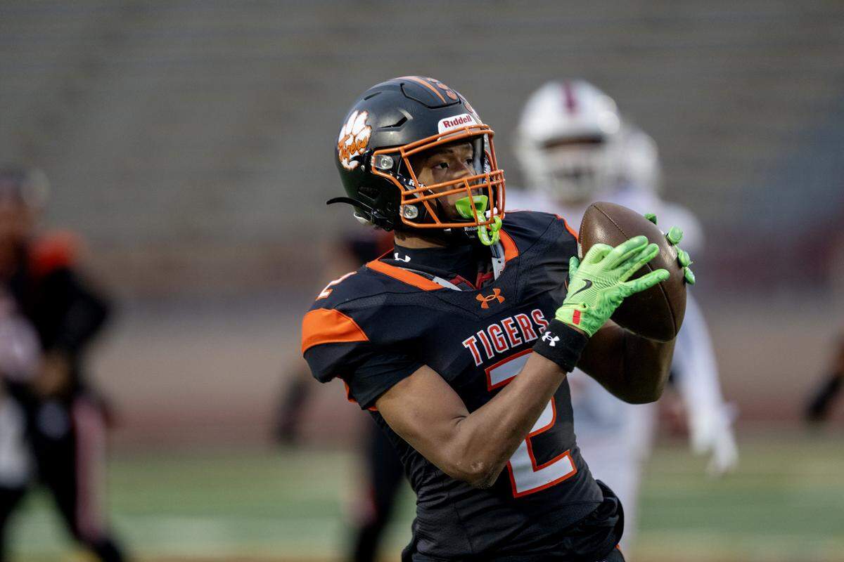 The Roseville Tigers' (JJ) Oreste Yong (2) catches a pass and runs in for a touchdown in the first half of the CIF Sac-Joaquin Section football Division lV championship against the East Union Lancers on Saturday at Hughes Stadium in Sacramento.