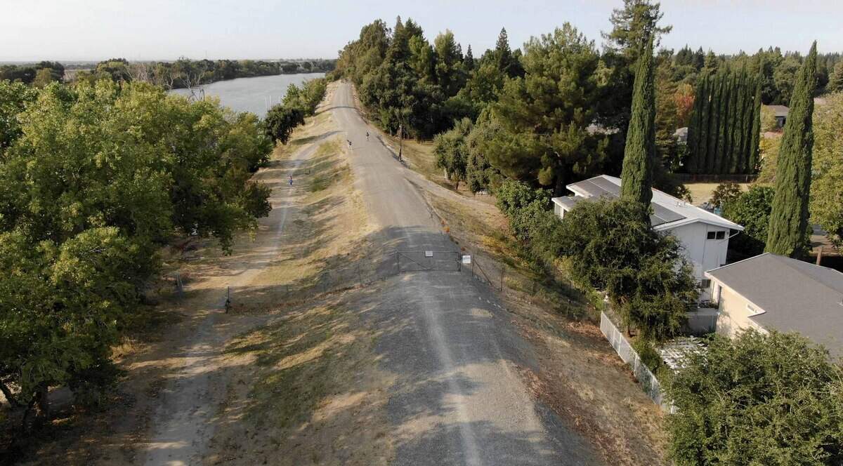 A cross-levee fence blocks a segment of Sacramento’s proposed  levee trail in the Pocket in 2019.