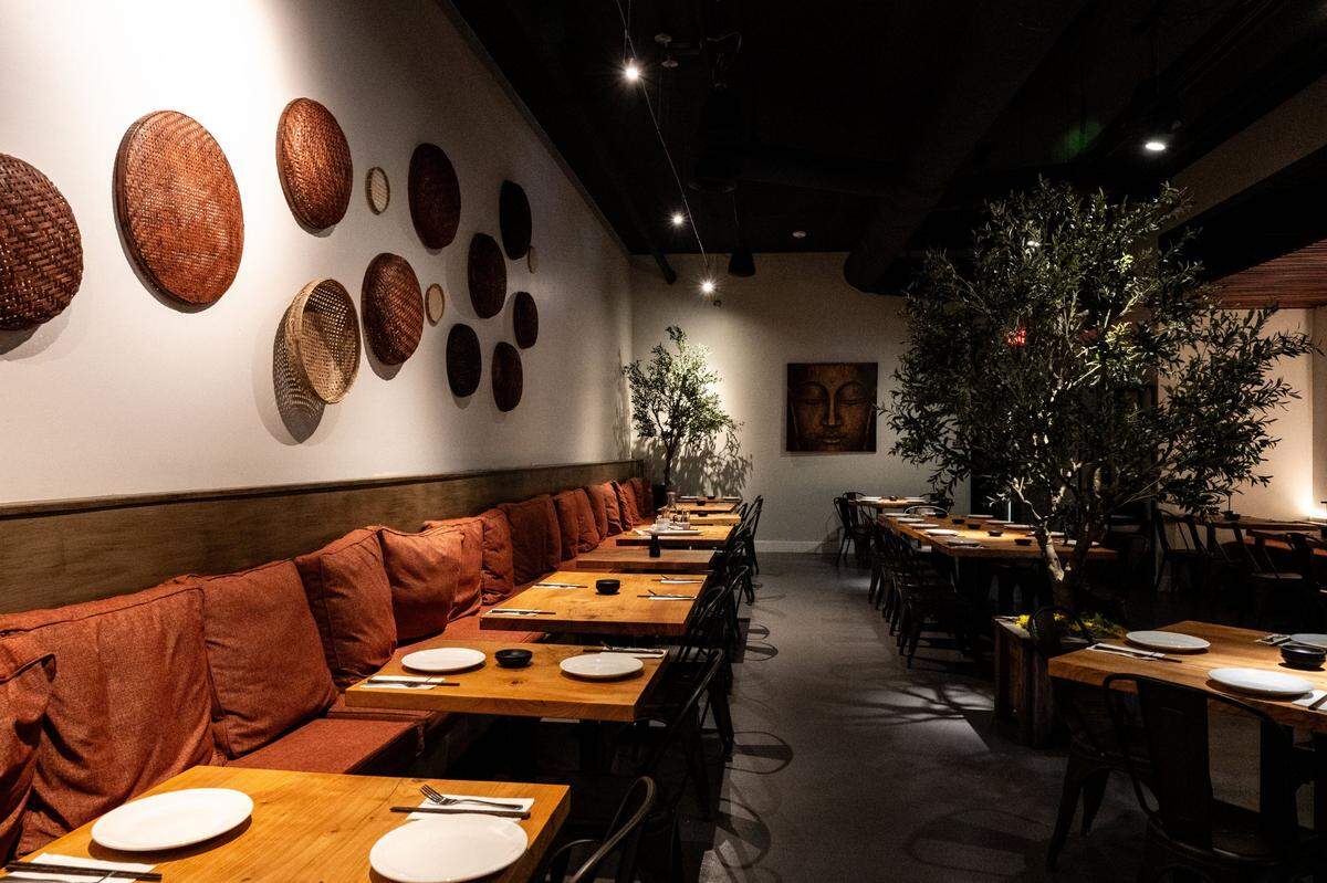 The seating area at Village of Om Plant Kitchen in Sacramento on July 1. The Newton Booth restaurant is serenely decorated with woven baskets on the wall, cushioned seating and dim lighting.