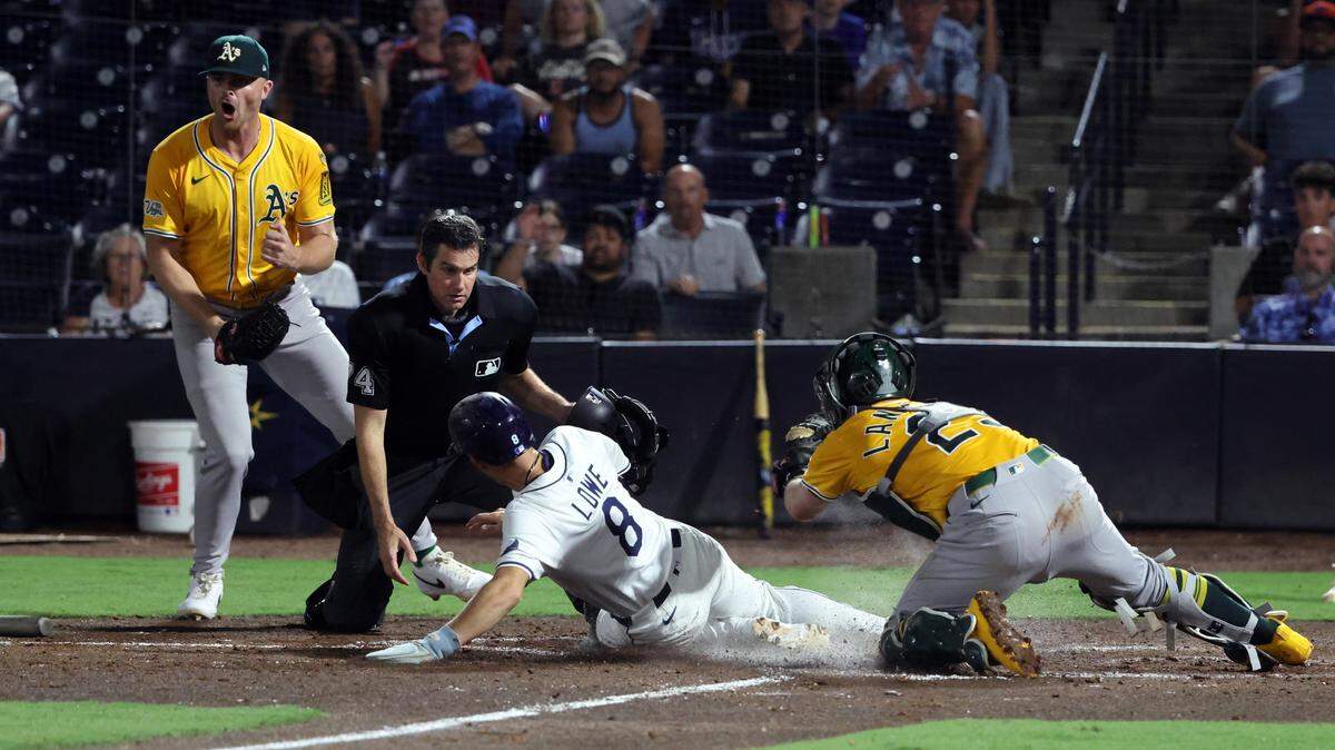 Jun 30, 2025; Tampa, Florida, USA;  Athletics catcher Shea Langeliers (23) tags out Tampa Bay Rays second base Brandon Lowe (8) at home plate as pitcher Michael Kelly (49) celebrates during the eighth inning at George M. Steinbrenner Field. Mandatory Credit: Kim Klement Neitzel-Imagn Images