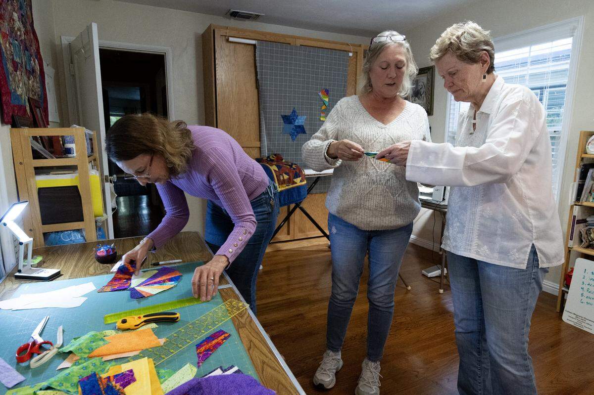 Jessa Kay Cruz, Dion Peart and Colleen Megowan-Romanowicz work on a quilt for a neighbor’s new baby in Sacramento on Friday, Nov. 7, 2025.