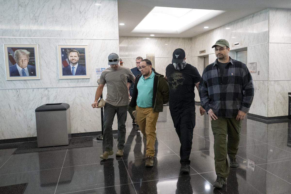 An individual is walked in handcuffs by federal authorities into a U.S. Immigrations and Customs Enforcement office in the John E. Moss federal building in downtown Sacramento on Wednesday, June 11, 2025.