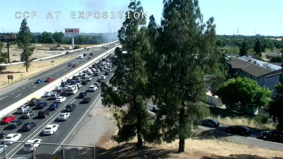 Smoke from a fire and a traffic backup are seen Sunday, June 30, 2024, from a Caltrans traffic camera on the Capital City Freeway at Exposition Boulevard in Sacramento.