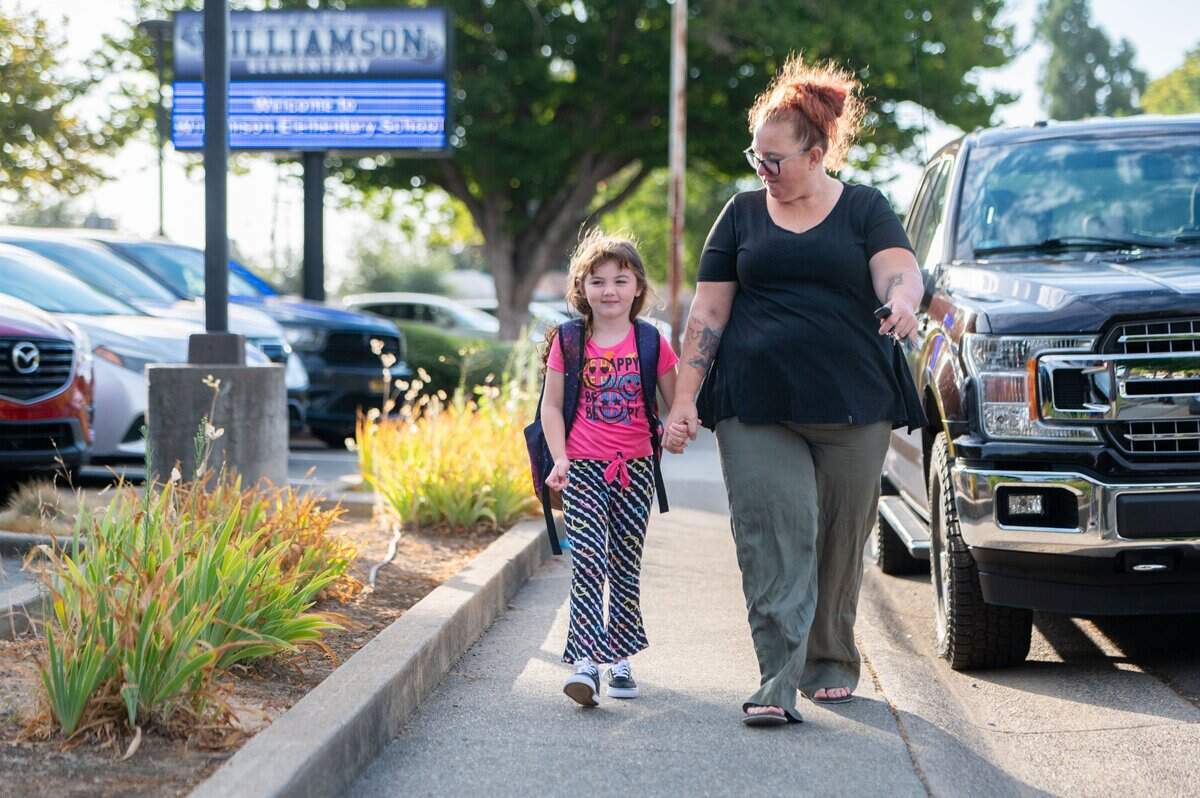Abigail Blunder, left, holds Kari Cool’s hand while walking to school for the first day of classes at Williamson Elementary School in Rancho Cordova on Thursday, Aug. 8, 2024. Cool said Bluder, who will be in second grade, is looking forward to seeing her friends.