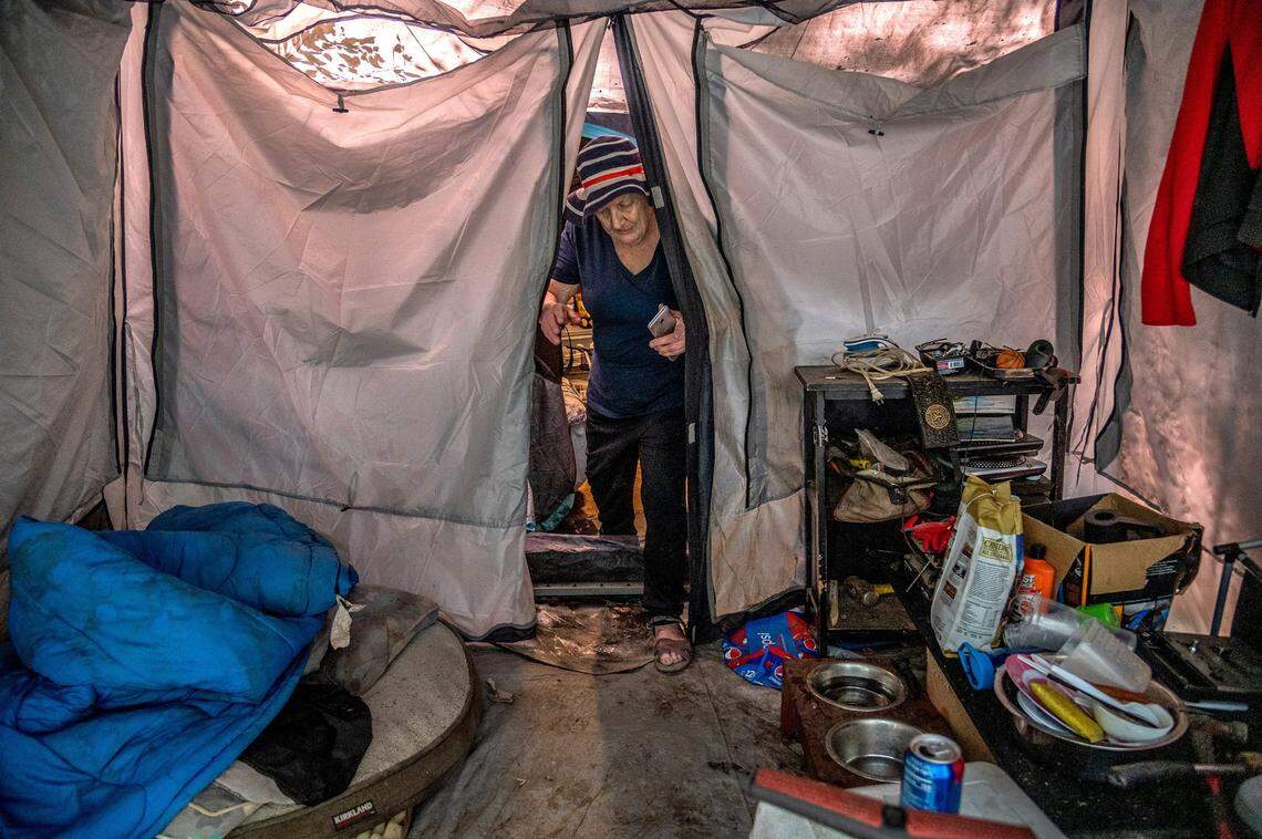 Patricia Berry, 72, steps through one of two tents belonging to her son where she stayed temporarily in June. She was facing several medical issues and is now in housing.