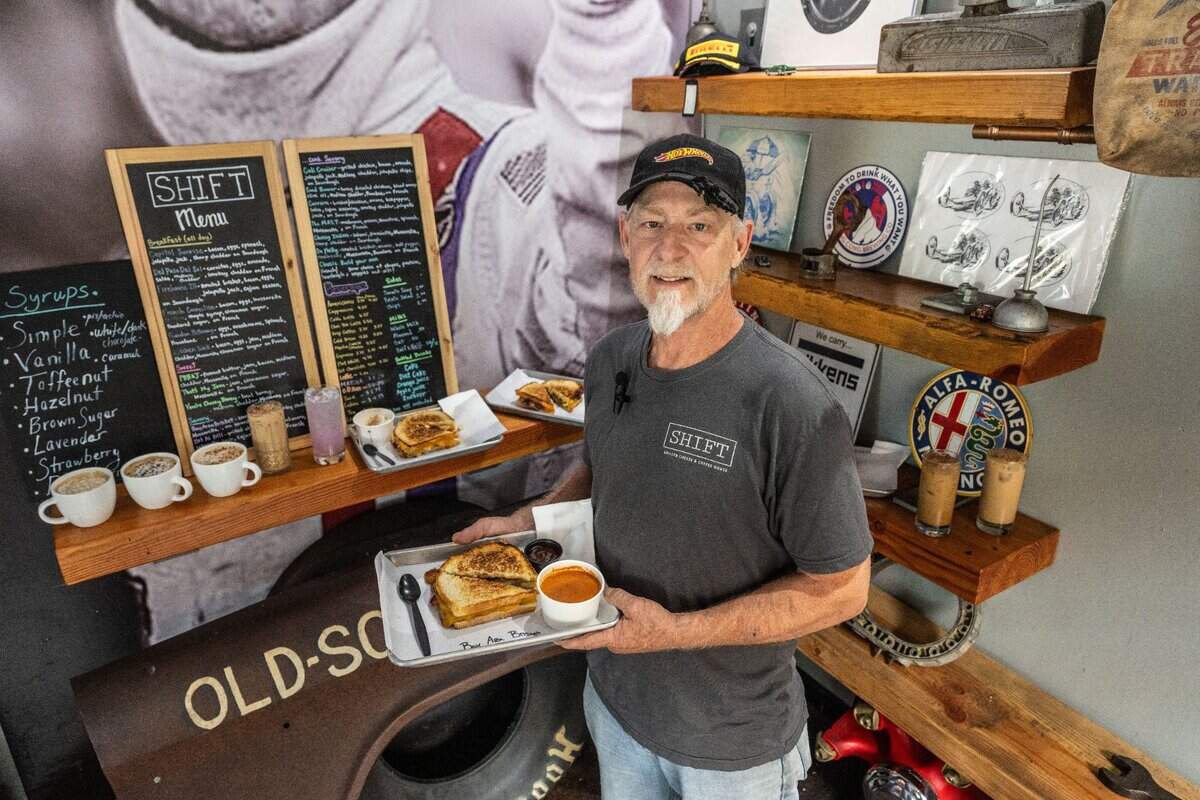 Mike Hollis, owner of Shift Coffee House, holds the Bay Area Brisket , signature grilled cheese sandwiches, on Wednesday, May 29, 2024. Hollis, a car enthusiast, decorated his coffee shop with automotive and racing memorabilia.