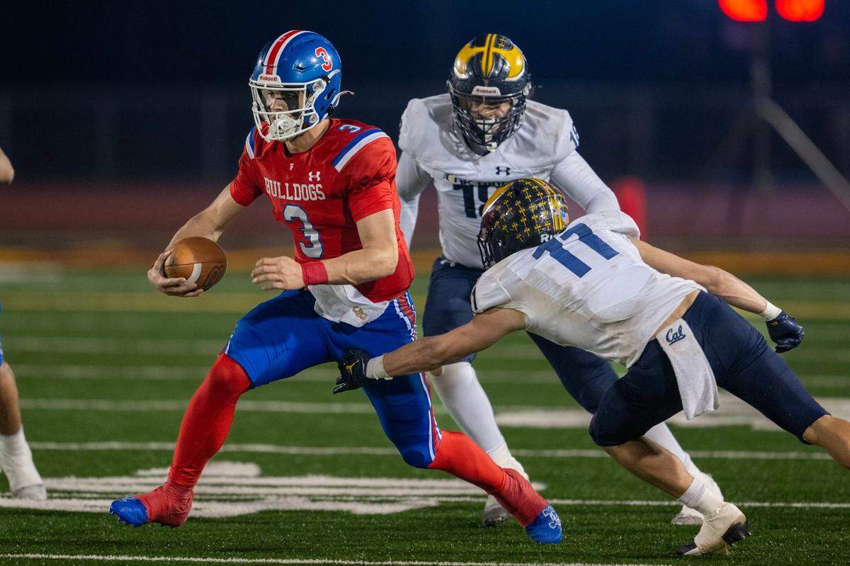 Folsom Bulldogs quarterback Ryder Lyons (3) evades the Oak Ridge Trojans’ Isaac Pierce (11) and Cole Esten (15) in the 2024 CIF Sac-Joaquin Section Division l football championship.