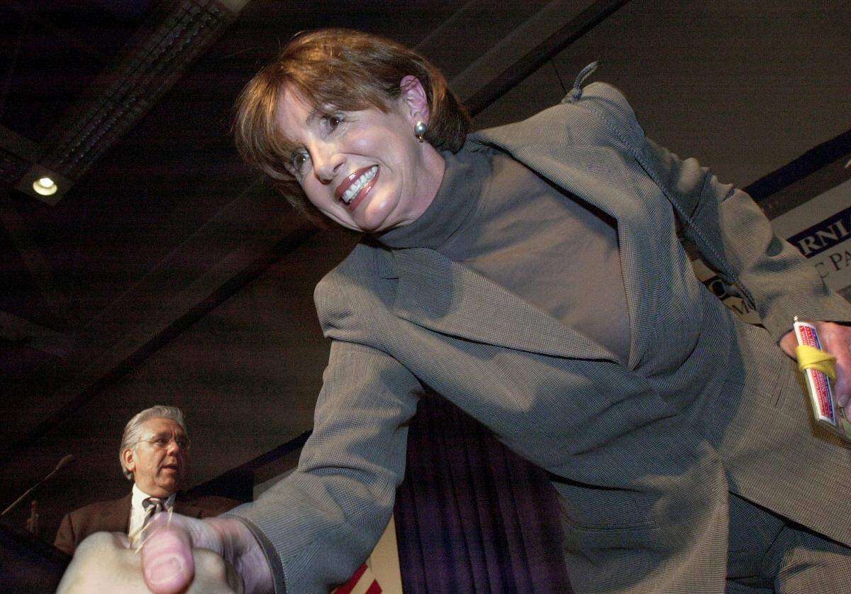 House Democratic Leader Nancy Pelosi shakes hands with a supporter following her introduction to delegates at the California Democratic Party state convention in Sacramento during a welcome reception March 14, 2003. In the background is California Democratic Party Chair Art Torres.