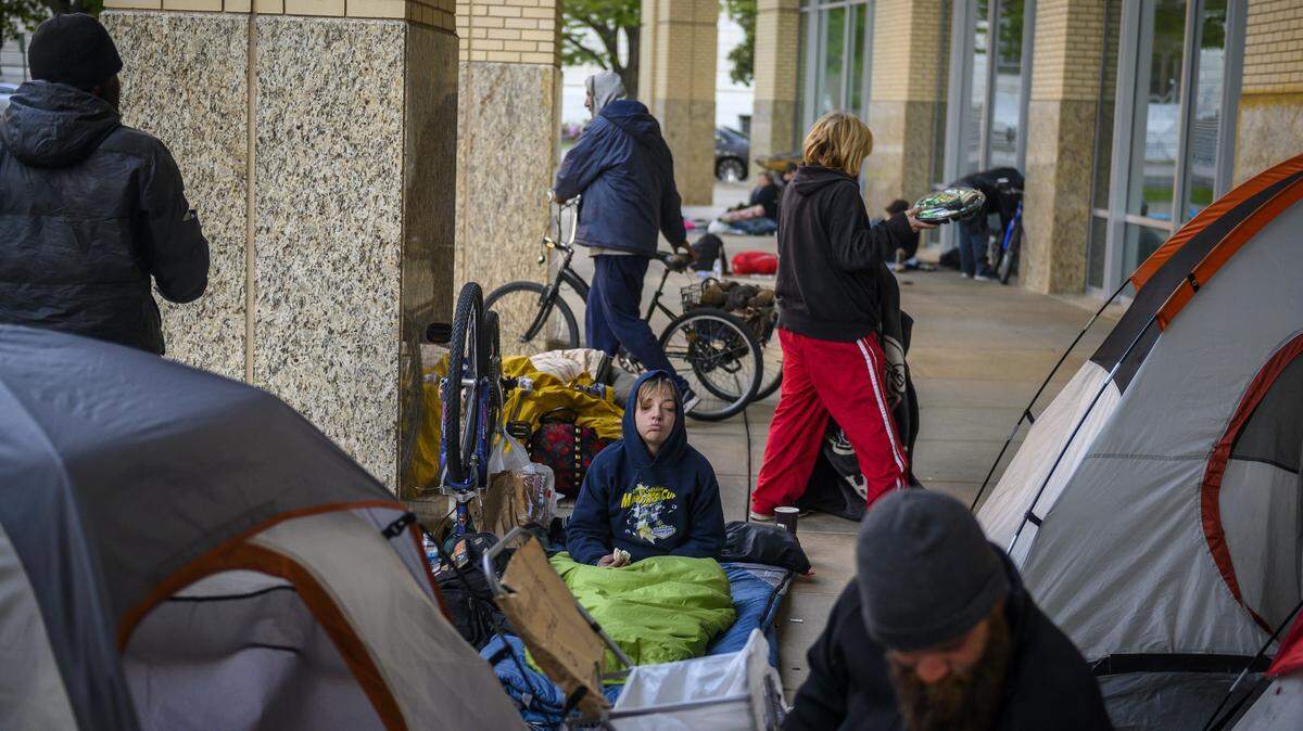 Janette Hayworth, middle, a person experiencing homelessness, eats a cookie as homeless campers start to clean up after police officers sweep the city hall grounds at 7 a.m. in downtown Sacramento, April 2, 2020.