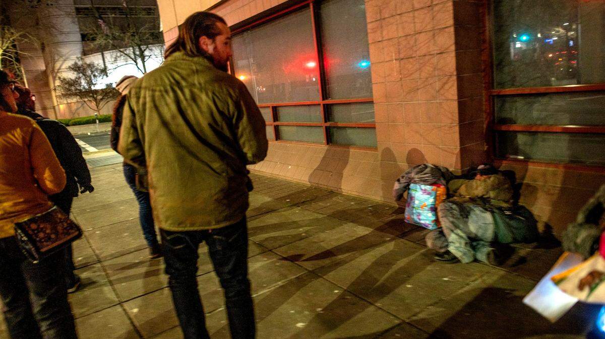 Volunteer Chris Martin walks past an unhoused person during the 2022 Sacramento Point-in-Time Count in downtown Sacramento in February. One of the rules during the count is not to disturb any homeless individuals who are sleeping.