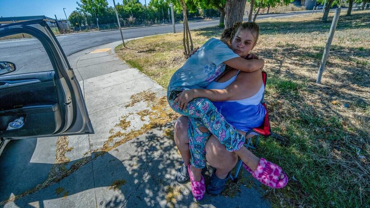 Selena Palaca, 10, embraces her mother, Tattiana Palaca, as they wait for gas after the family ran out of fuel at the intersection of Rio Linda Boulevard and North Avenue in Sacramento on Tuesday, June 30, 2026. "We have no gas, and we're hungry. We haven't eaten all day," Palaca said. After calling a list of shelters with her caseworker, she added, "I don't know where to go. There is nothing out there."