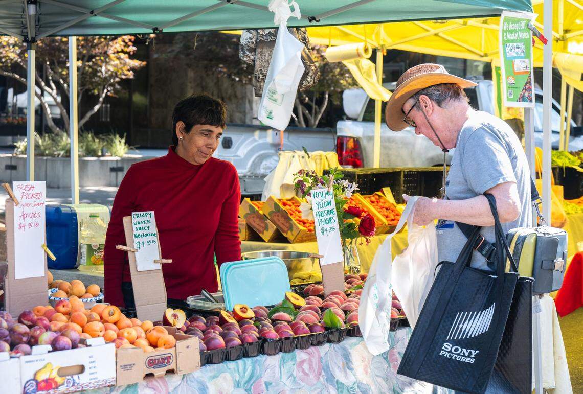 Magda Morgan, left, watches while a customer selects produce from her stand at the Capitol Mall Farmers’ Market on Wednesday. Morgan has been a vendor for 42 years.